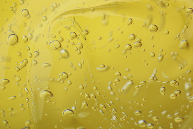 Photo of Pure transparent cosmetic gel on yellow background, closeup