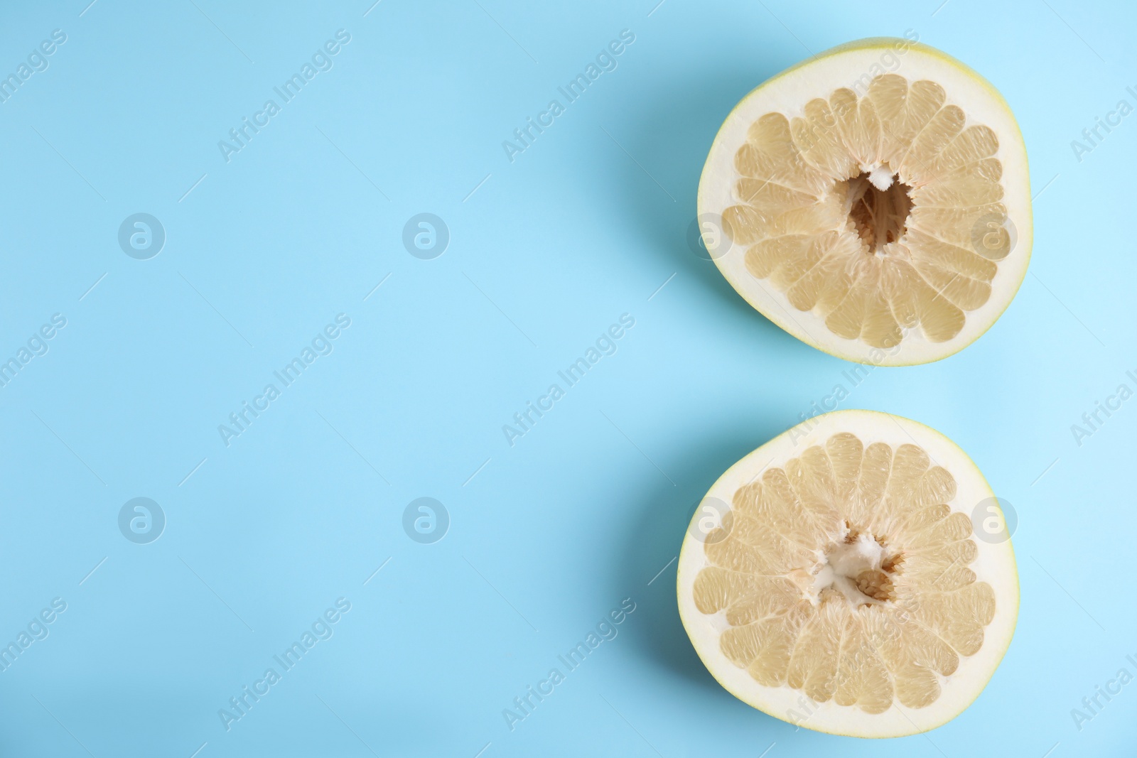 Photo of Fresh cut pomelo fruit on light blue background, flat lay. Space for text