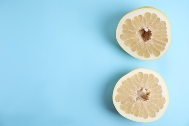 Photo of Fresh cut pomelo fruit on light blue background, flat lay. Space for text