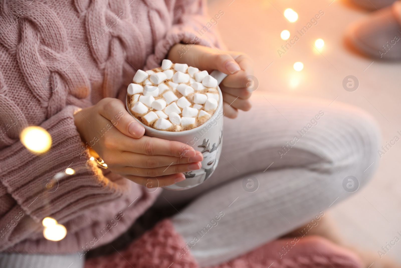 Photo of Woman holding cup of hot drink with marshmallows indoors, closeup. Magic Christmas atmosphere