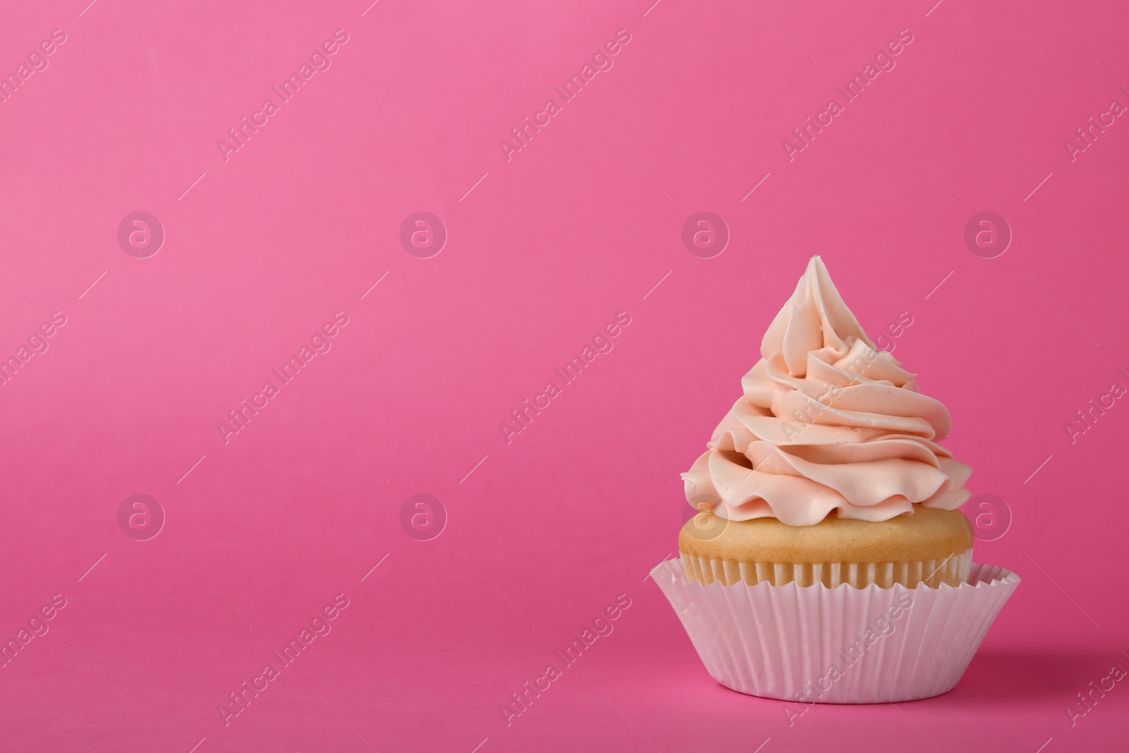 Photo of Tasty cupcake with cream on pink background, space for text