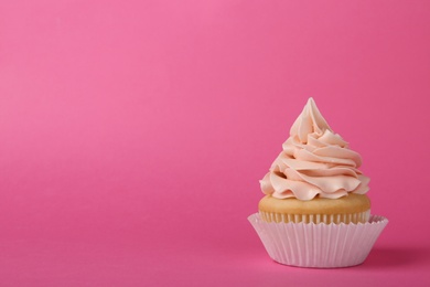 Tasty cupcake with cream on pink background, space for text