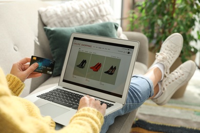 Photo of Woman with credit card using laptop for online shopping at home, closeup