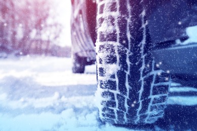 Car with winter tires on snowy road, closeup view. Space for text