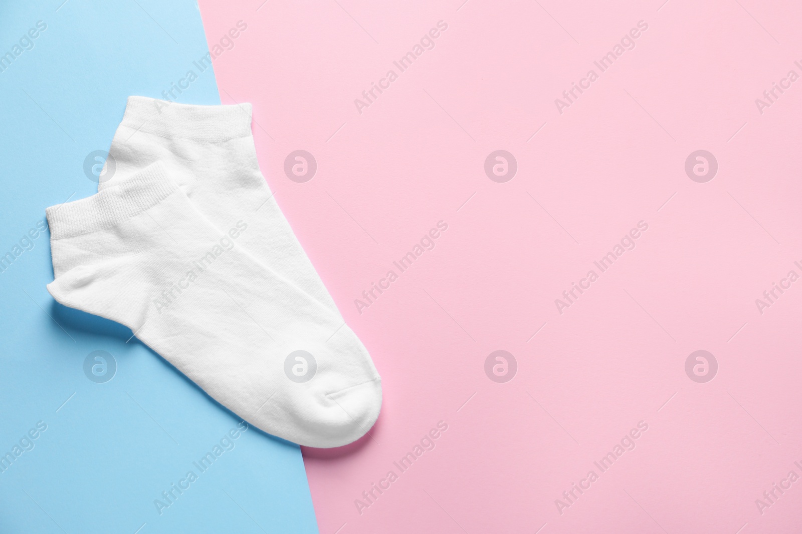 Photo of Pair of white socks on colorful background, flat lay. Space for text