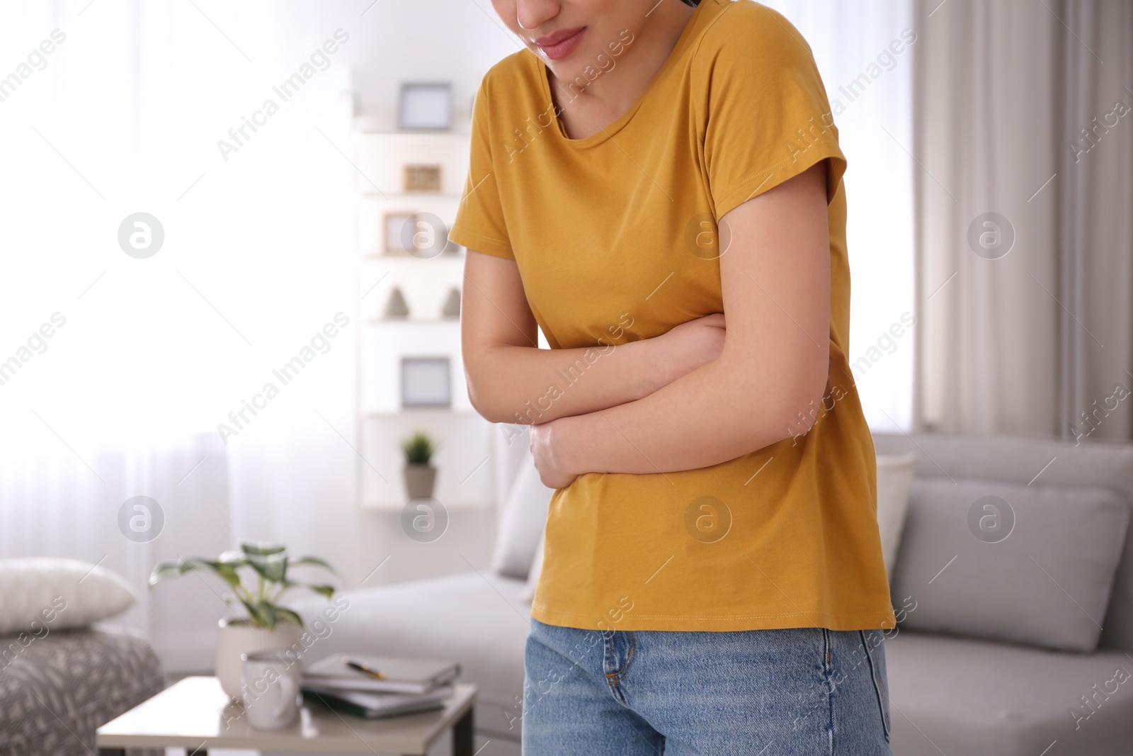 Photo of Young woman suffering from stomach ache at home, space for text. Food poisoning