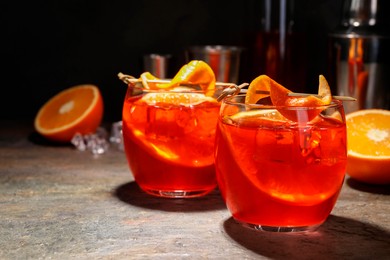 Photo of Aperol spritz cocktail, ice cubes and orange slices in glasses on grey textured table, closeup. Space for text