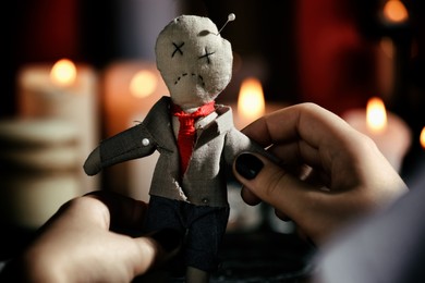 Photo of Woman holding voodoo doll with pins indoors, closeup. Curse ceremony