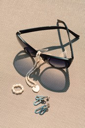 Stylish sunglasses and jewelry on grey surface