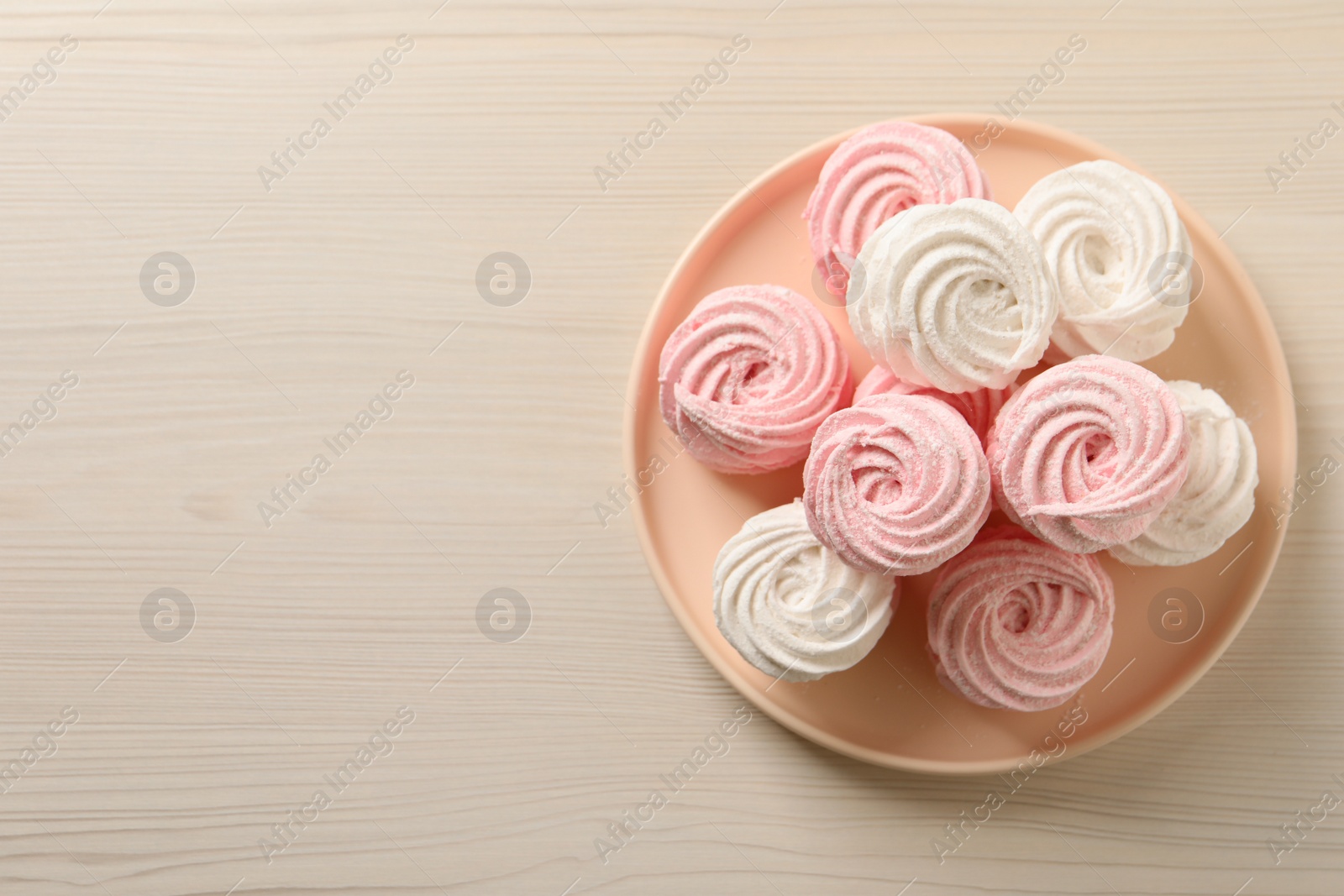Photo of Plate with delicious marshmallows on wooden table, top view. Space for text