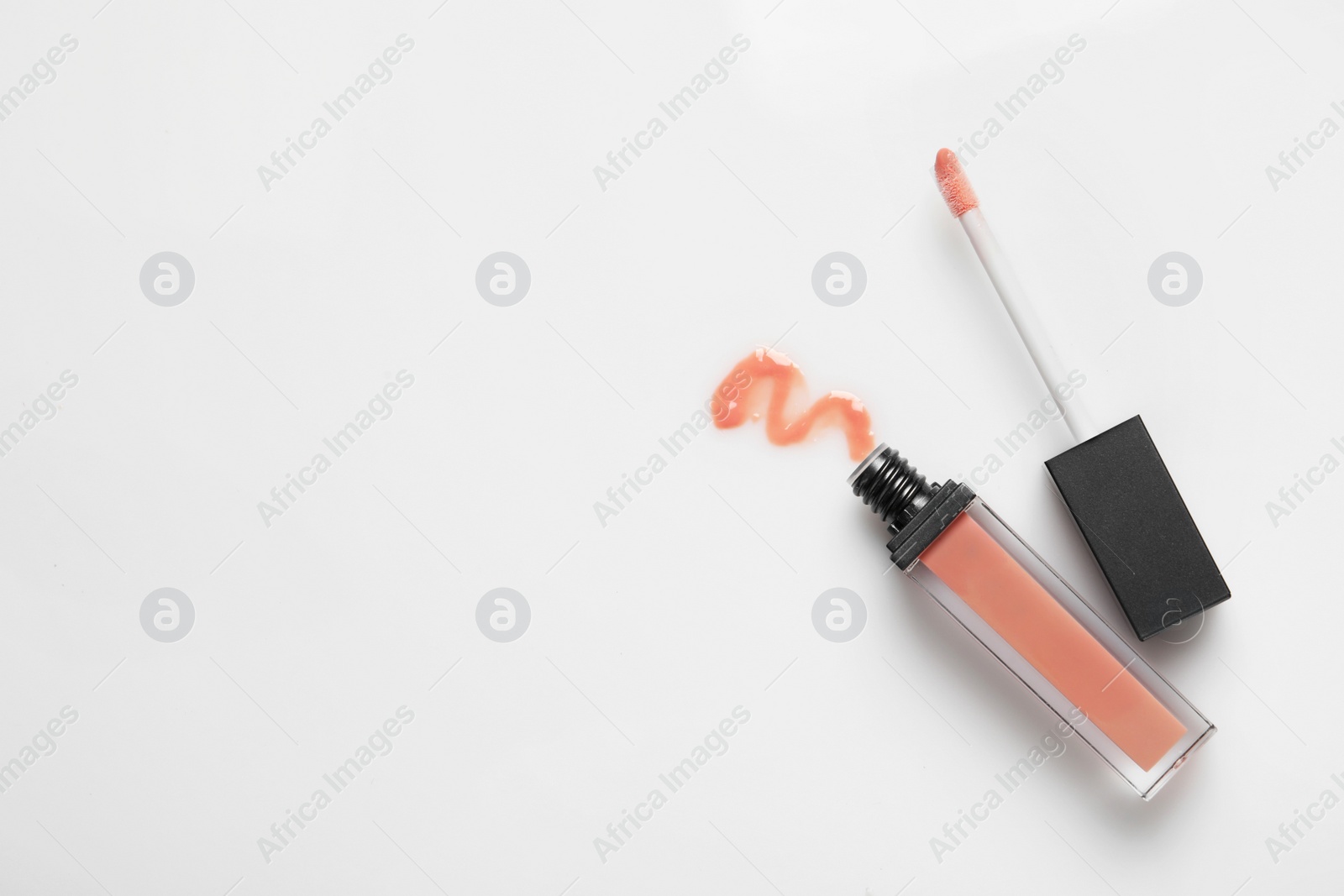 Photo of Beige liquid lipstick with smear and applicator isolated on white, top view. Space for text
