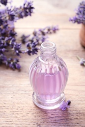 Photo of Glass bottle of natural cosmetic oil and lavender flowers on wooden table