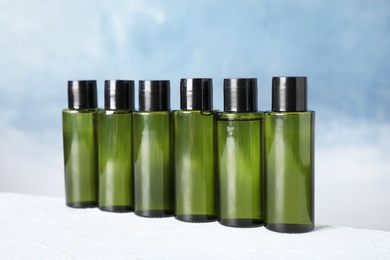 Mini bottles with cosmetic products on white table against blue background