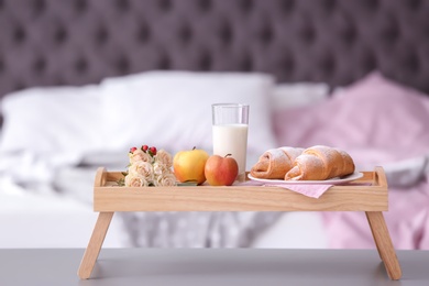 Tray with delicious croissants, milk and apples on table