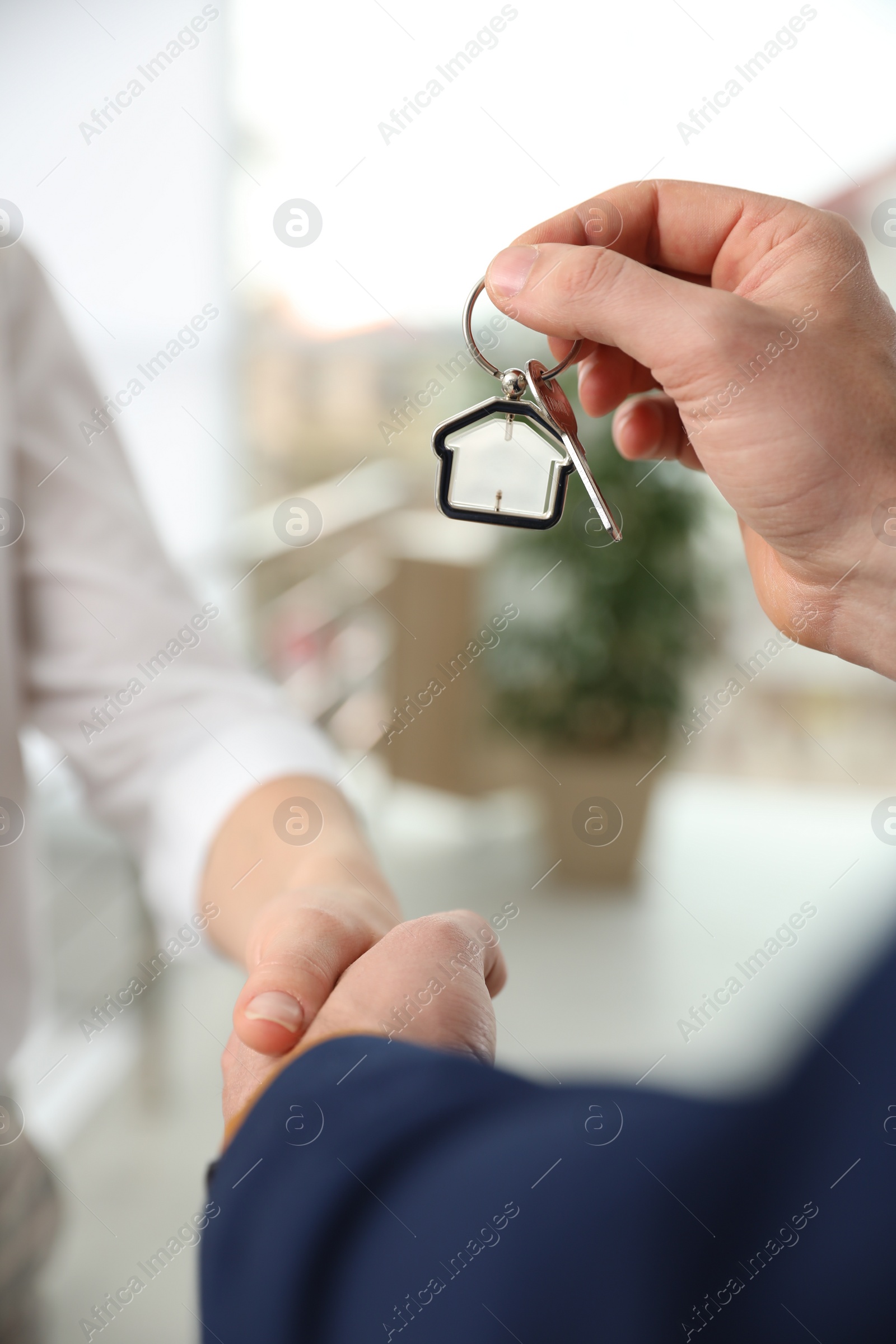 Photo of Real estate agent giving key with trinket to client in office, closeup