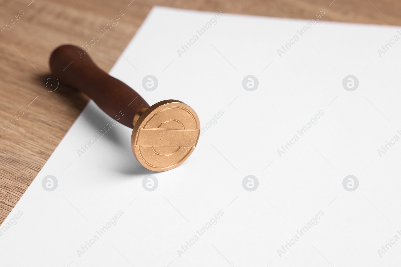 Photo of One stamp tool and sheet of paper on wooden table, closeup. Space for text