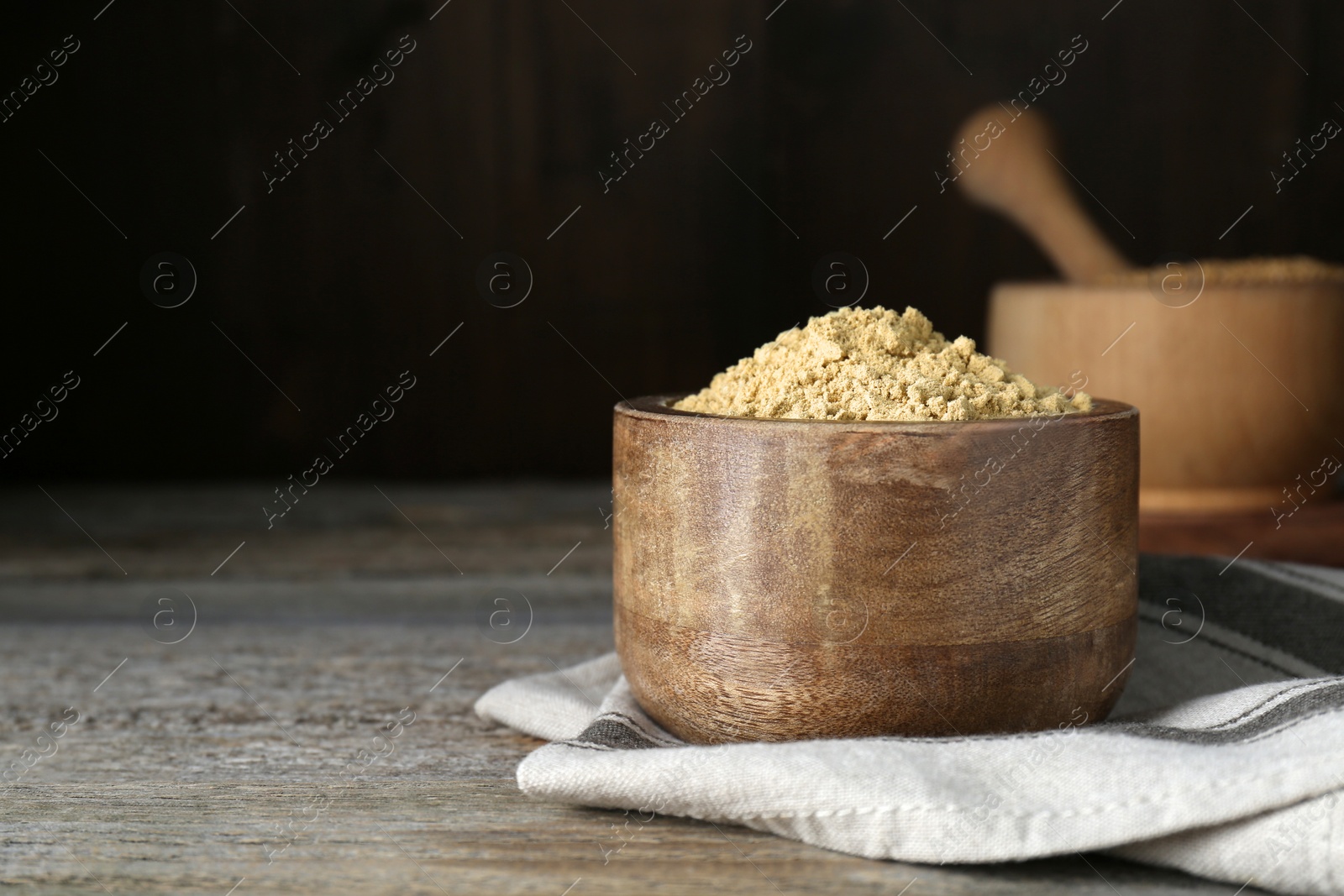 Photo of Bowl of mustard powder on wooden table. Space for text