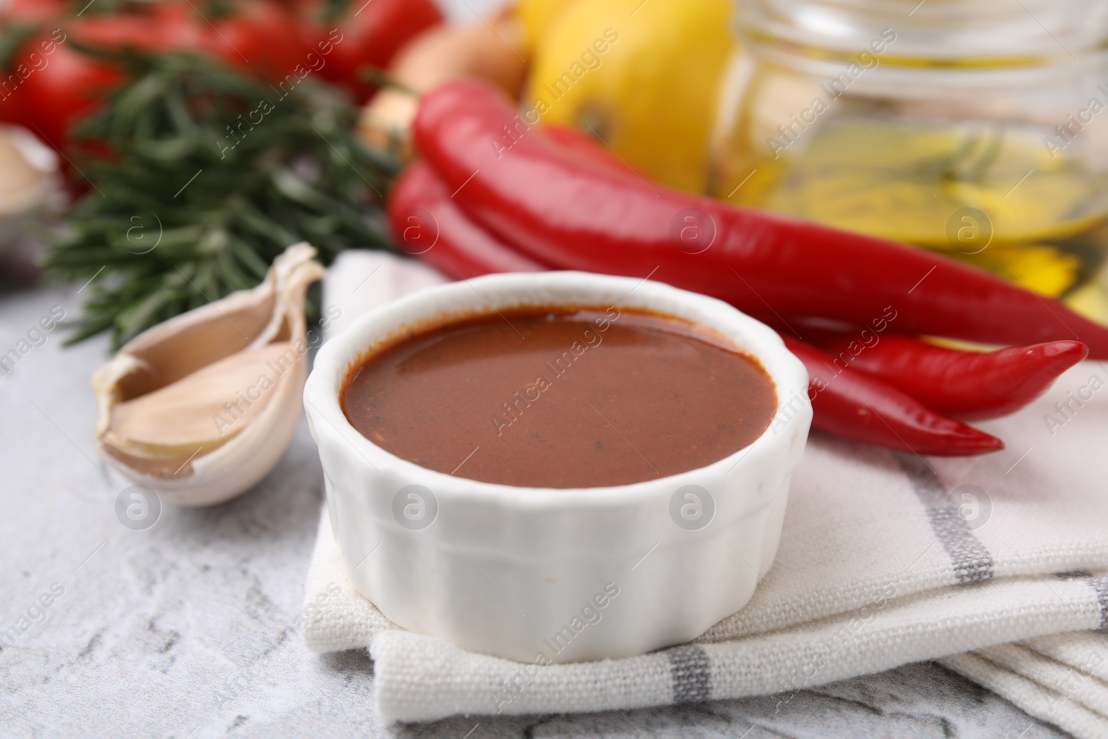 Photo of Fresh marinade and different ingredients on light grey textured table, closeup