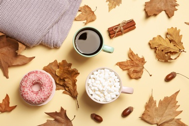 Flat lay composition with hot cozy drinks and autumn leaves on color background