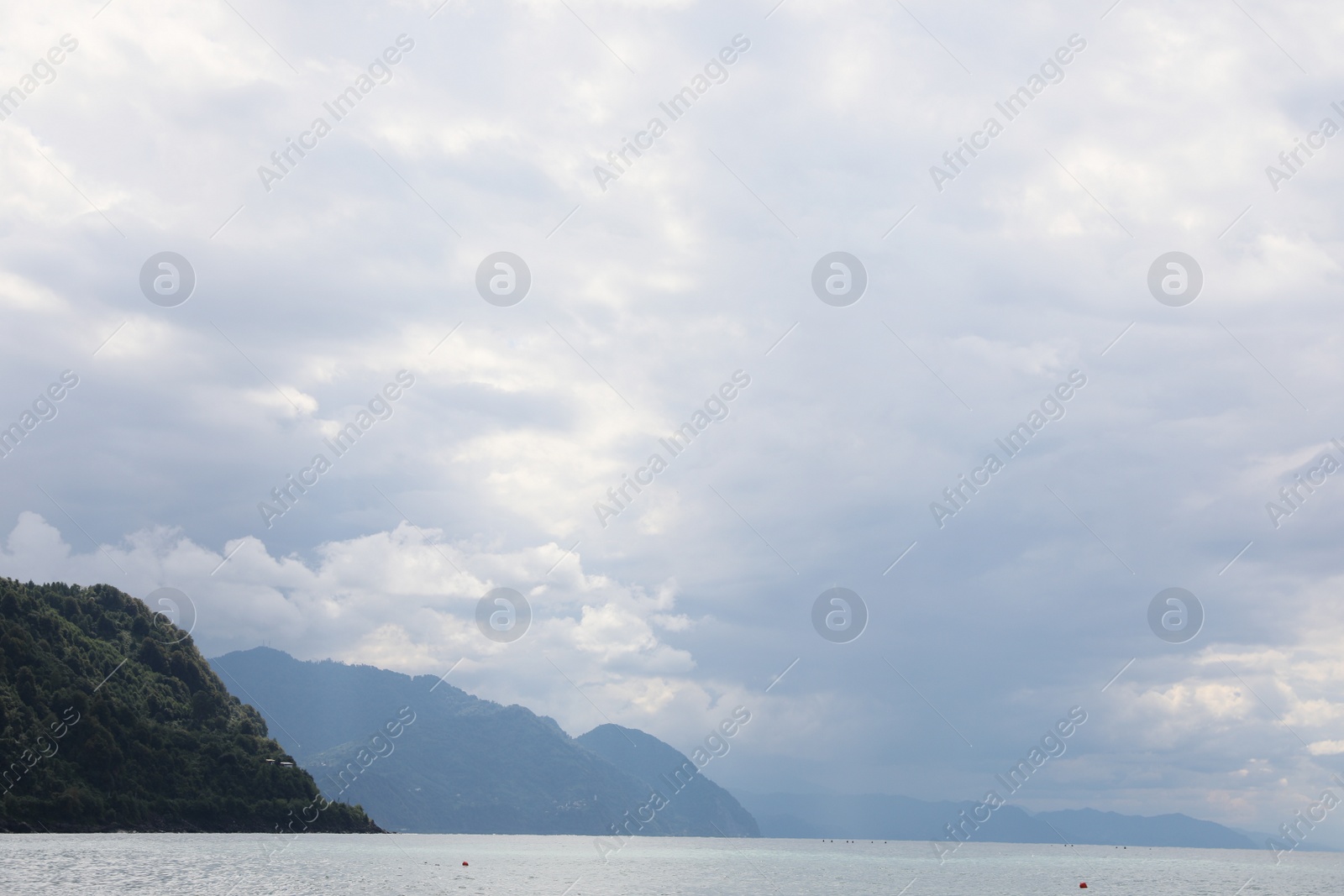 Photo of Picturesque view of beautiful sea and hills under sky with fluffy clouds