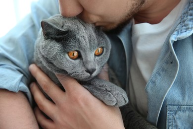 Man with cute cat indoors, closeup view