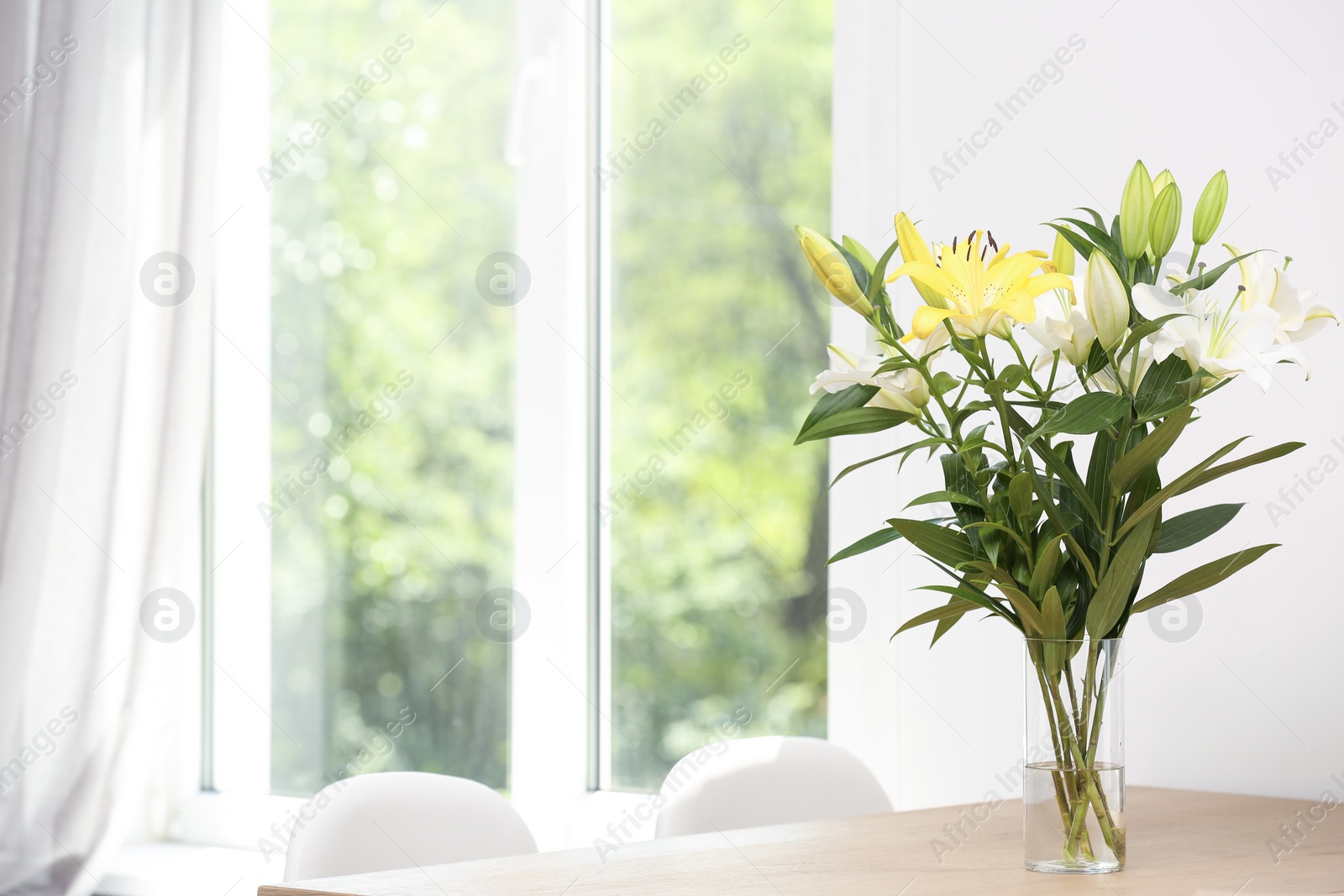 Photo of Vase with bouquet of beautiful lilies on wooden table indoors. Space for text