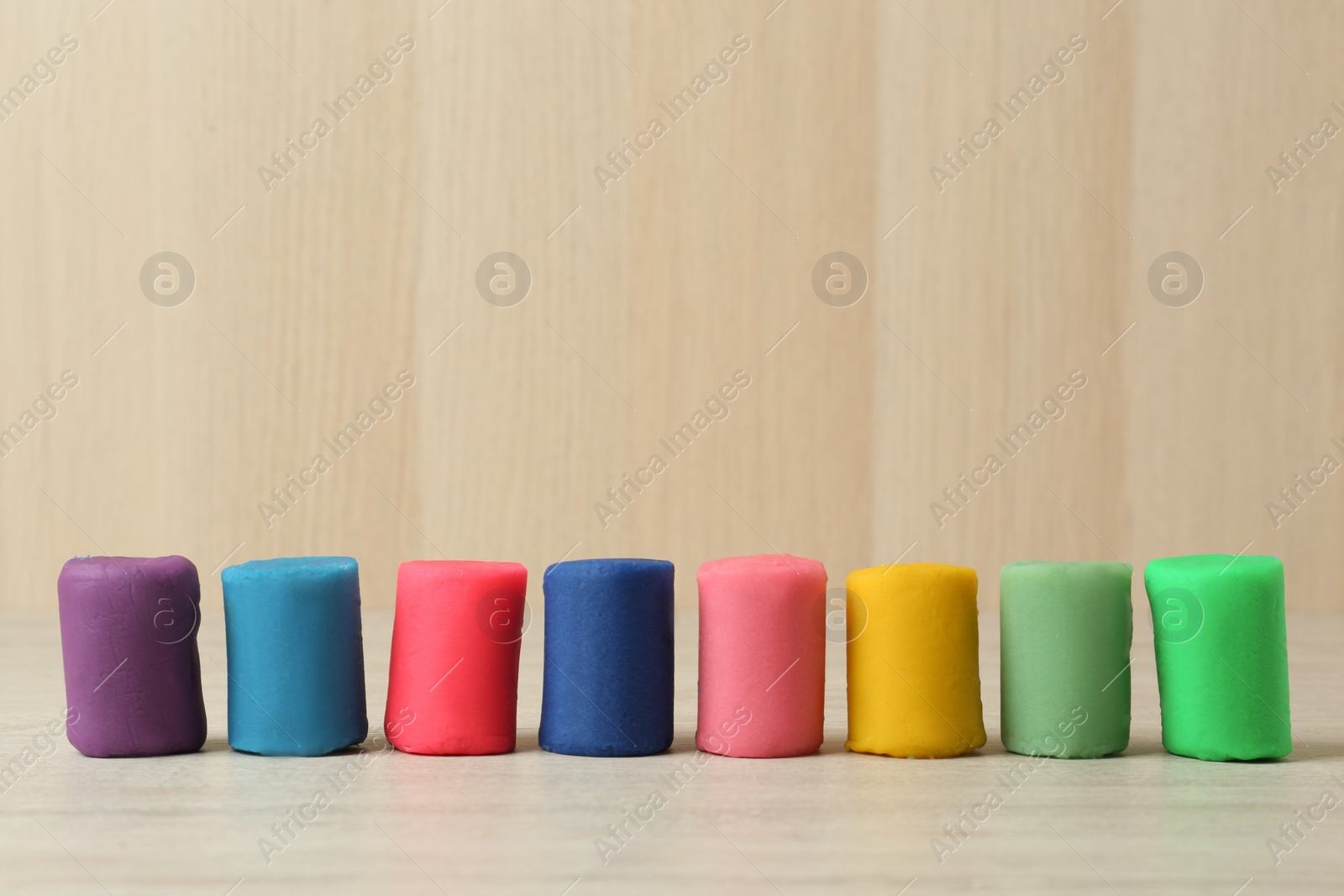 Photo of Different color play dough on white wooden table. Space for text