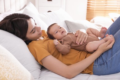 Happy young mother with her cute baby on bed at home