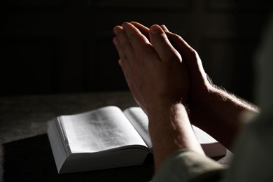 Photo of Religion. Christian man praying over Bible at table, closeup. Space for text