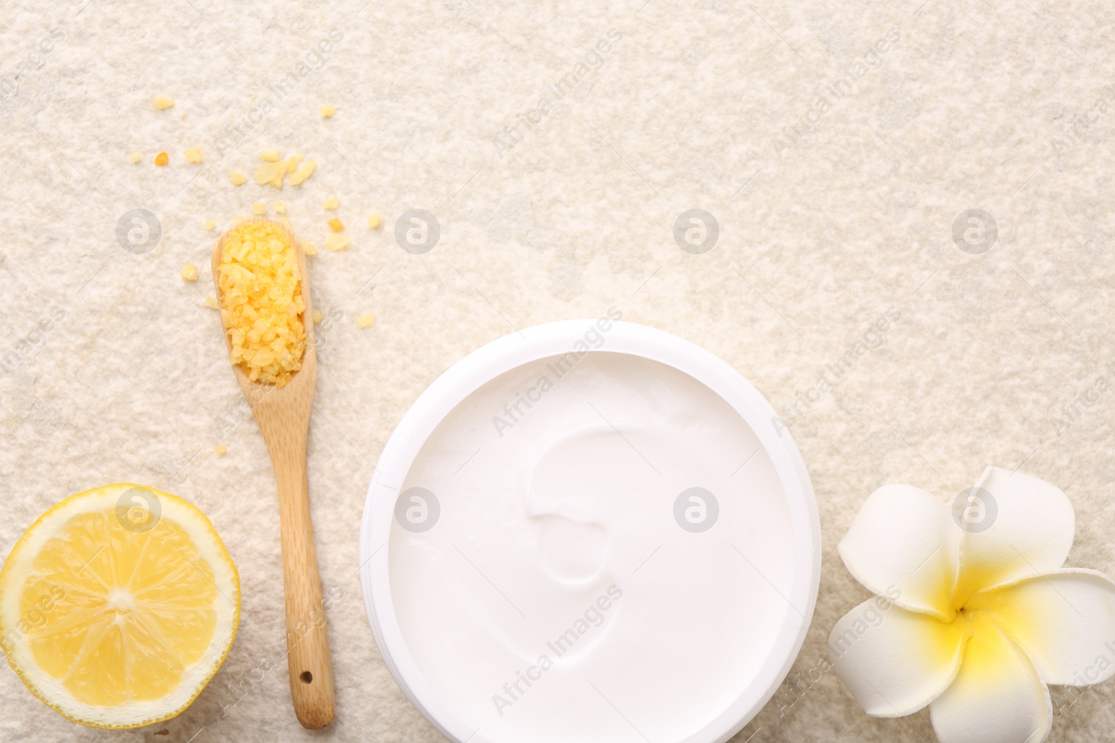 Photo of Flat lay composition with moisturizing cream in open jar and other body care products on light textured table