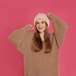 Photo of Beautiful young woman in hat and sweater on pink background. Winter season