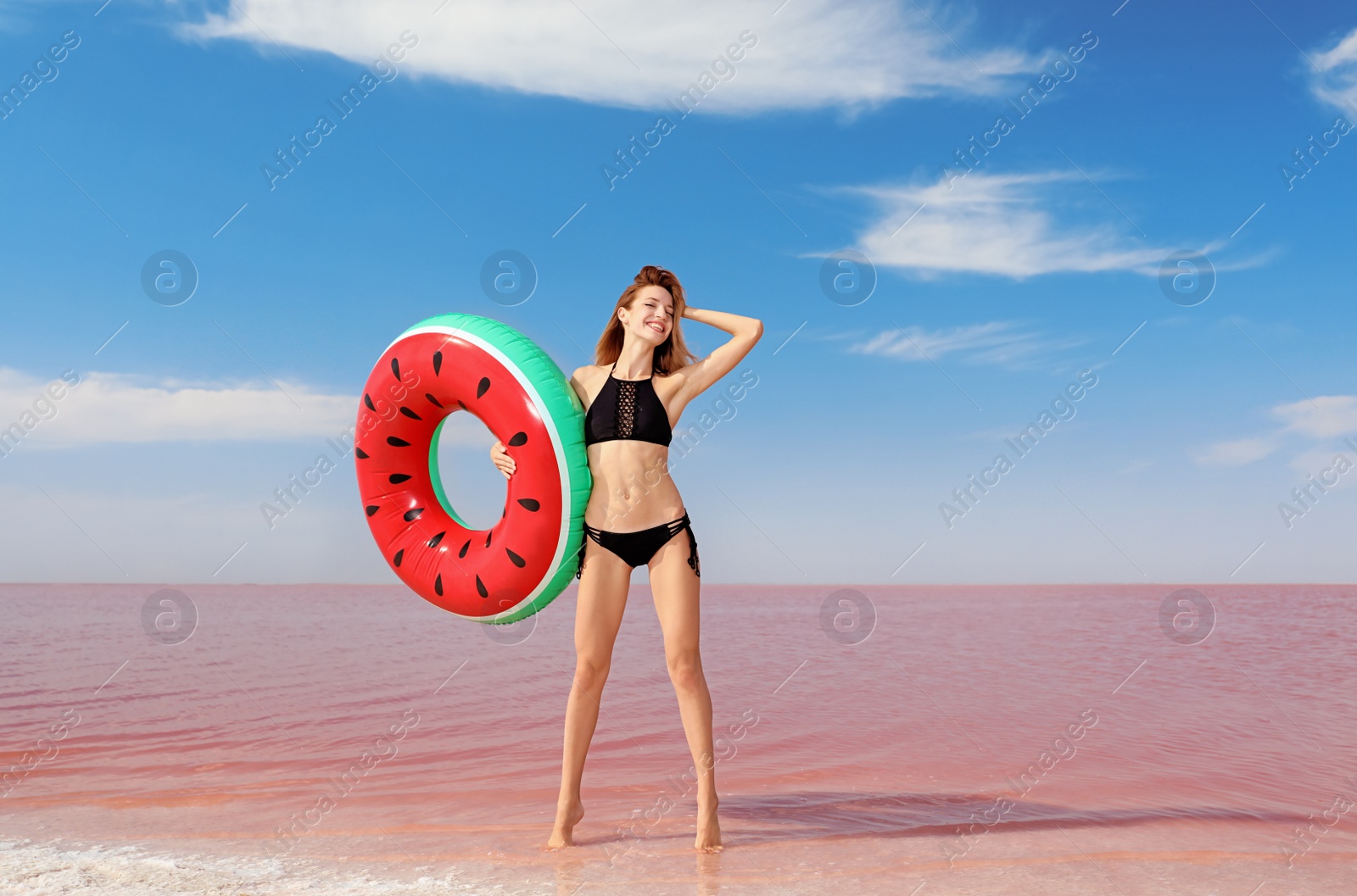 Photo of Beautiful woman with inflatable ring posing near pink lake on sunny day