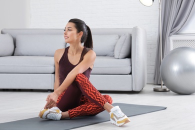 Photo of Young woman in fitness clothes doing exercise at home