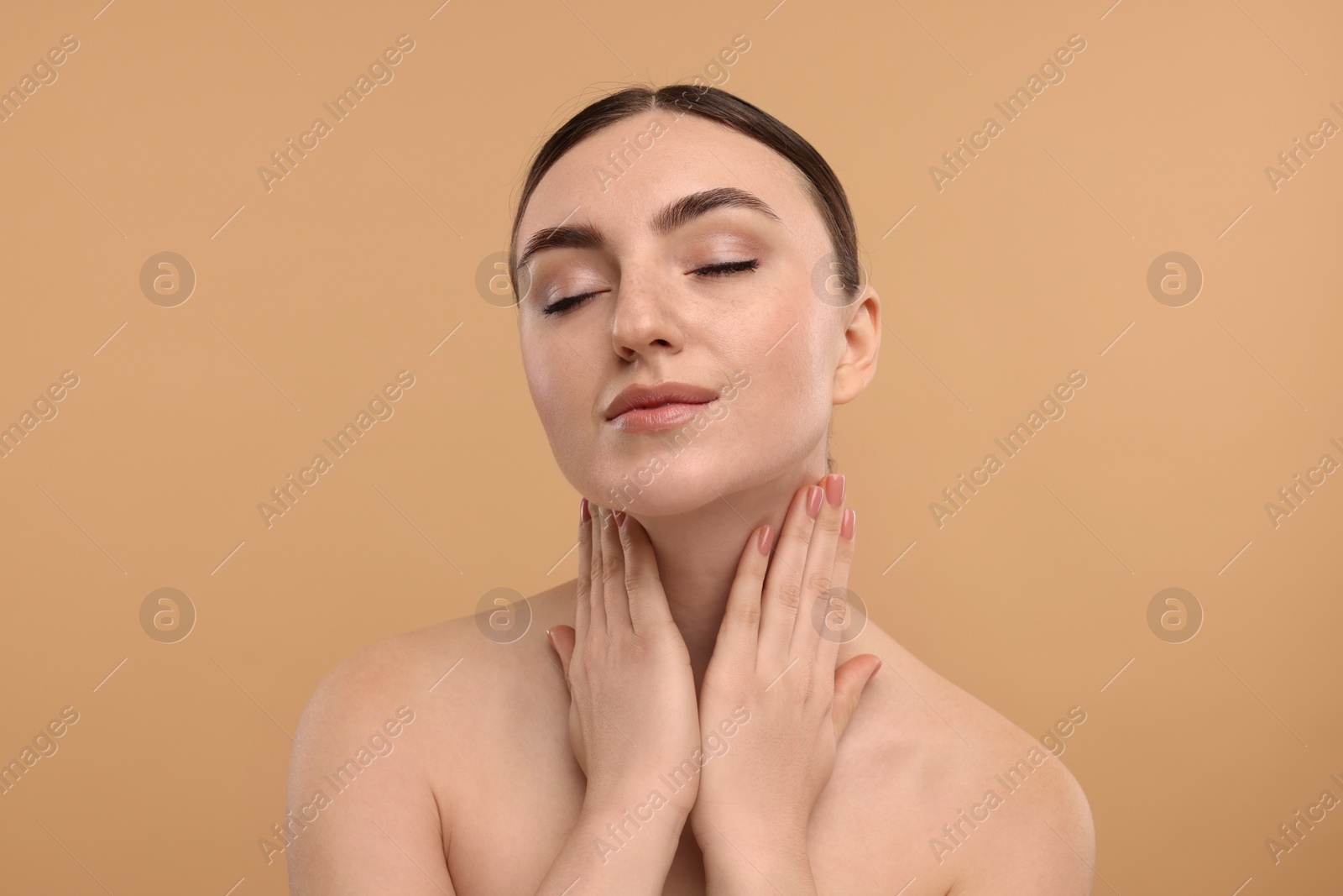 Photo of Beautiful woman touching her neck on beige background