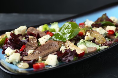 Photo of Delicious salad with beef tongue and cheese on black table, closeup