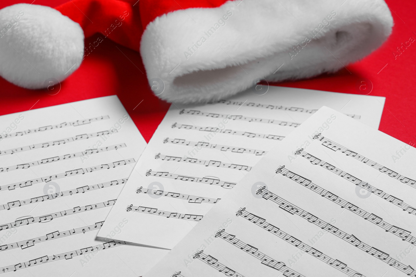 Photo of Note sheets and Santa hat on red background