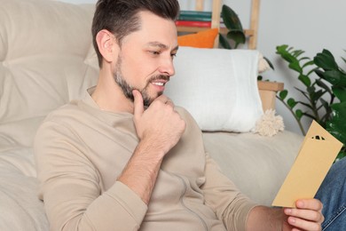 Man reading greeting card on sofa in living room