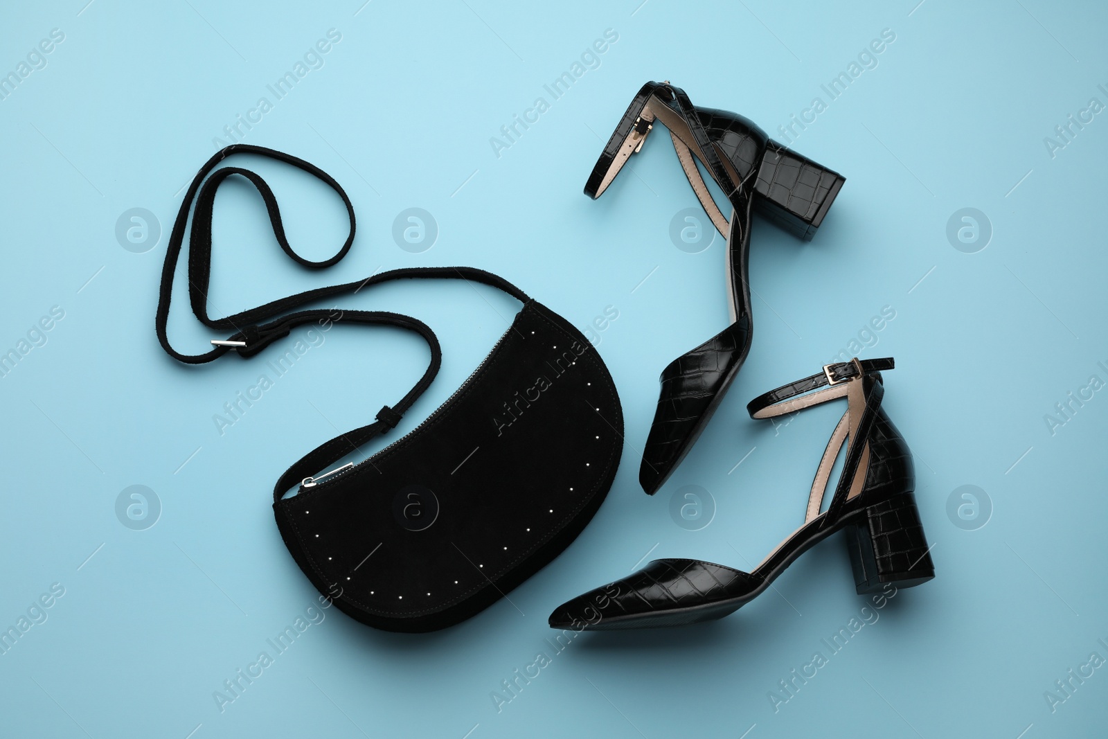 Photo of Stylish woman's bag and shoes on light blue background, flat lay
