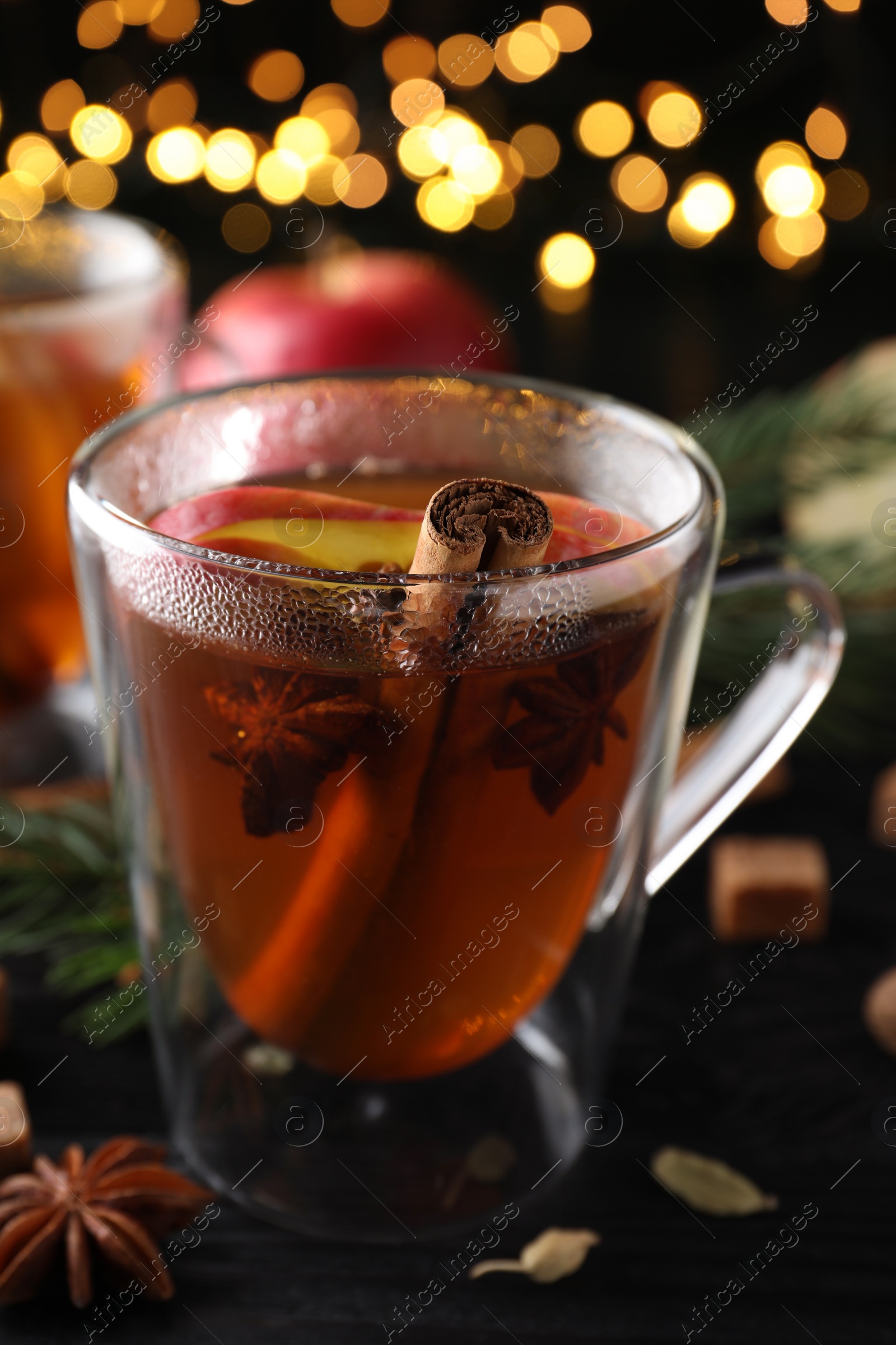 Photo of Aromatic hot mulled cider on black wooden table, closeup