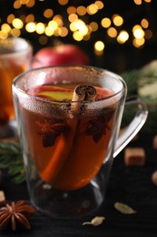 Photo of Aromatic hot mulled cider on black wooden table, closeup