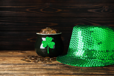 Photo of Green leprechaun hat and pot with gold coins on wooden table. St. Patrick's Day celebration