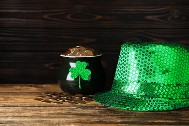 Green leprechaun hat and pot with gold coins on wooden table. St. Patrick's Day celebration