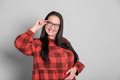 Photo of Beautiful overweight woman in eyeglasses on light grey background. Space for text