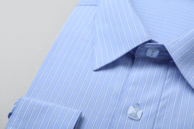 Photo of Stylish light blue shirt on white background, closeup. Dry-cleaning service