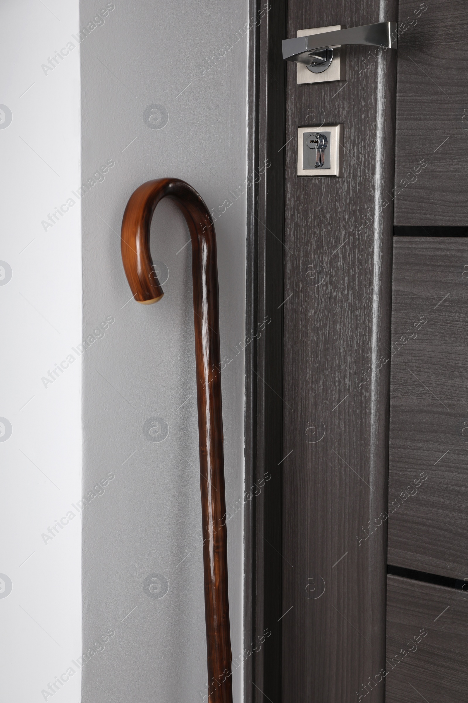 Photo of Elegant wooden walking cane near door indoors