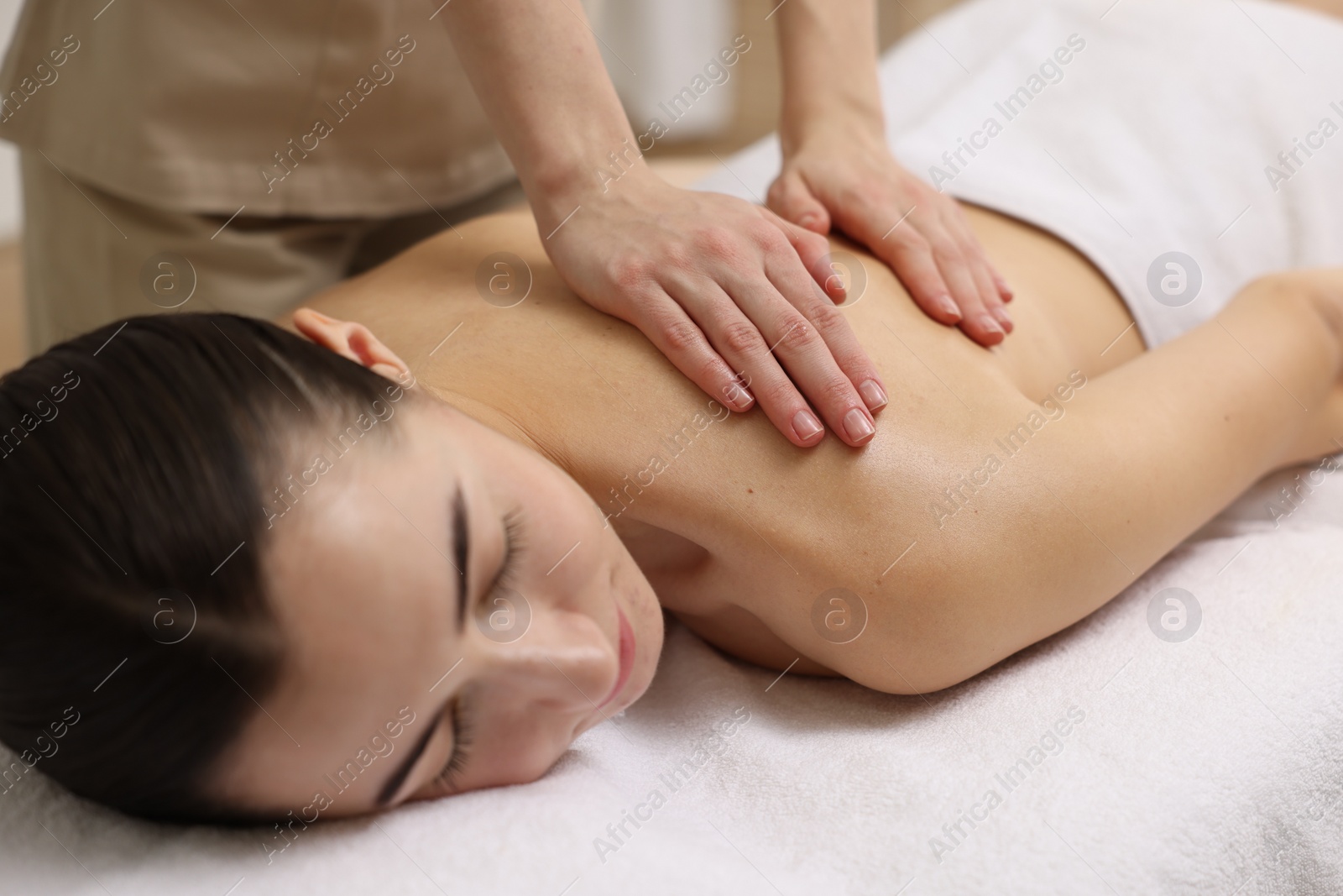 Photo of Woman receiving back massage on couch in spa salon