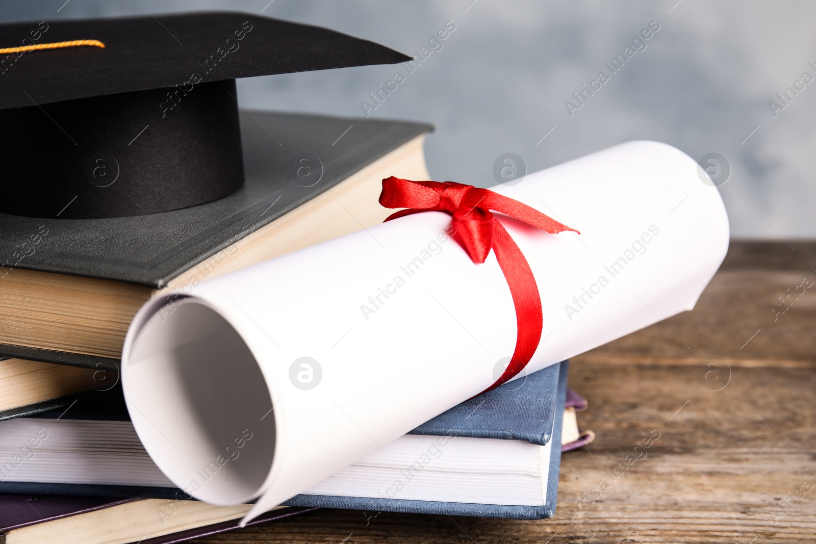 Photo of Graduation hat, books and student's diploma on wooden table