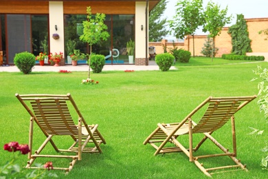 Wooden deck chairs in beautiful garden on sunny day