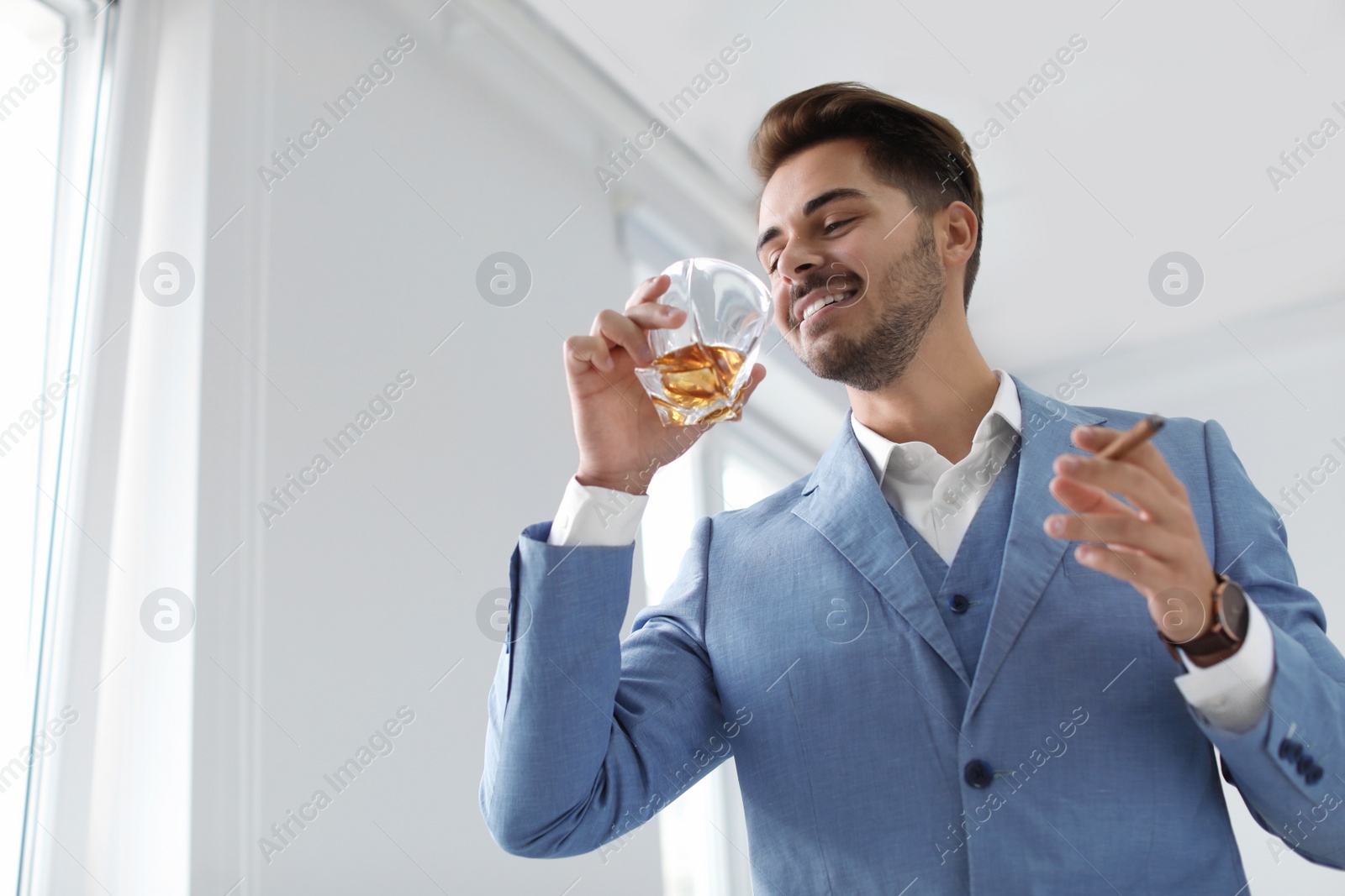 Photo of Man with glass of whiskey and cigar indoors