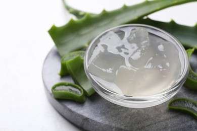 Photo of Aloe vera gel and slices of plant on white background, closeup. Space for text